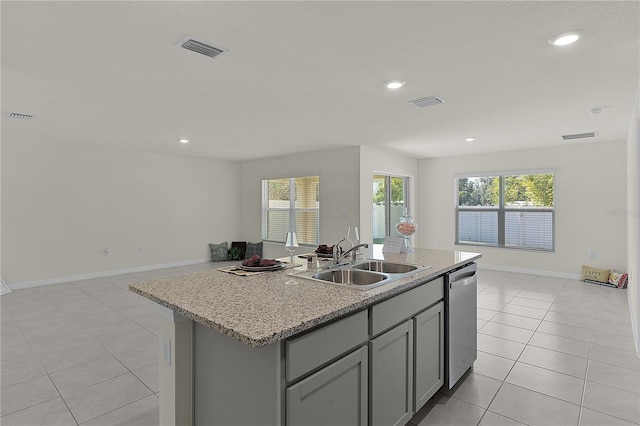 kitchen with sink, light tile patterned floors, dishwasher, gray cabinetry, and an island with sink