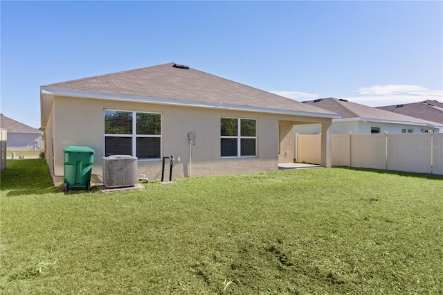 rear view of house featuring a lawn and central air condition unit