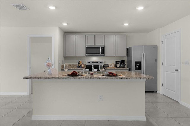 kitchen featuring light tile patterned floors, gray cabinets, stainless steel appliances, and a center island with sink