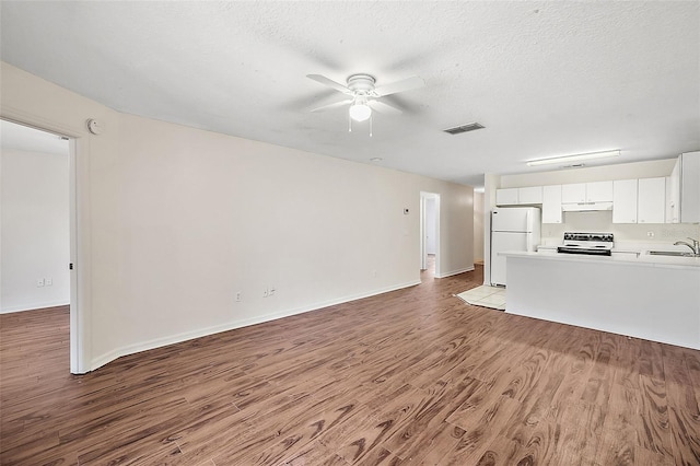 unfurnished living room with ceiling fan, sink, a textured ceiling, and light hardwood / wood-style flooring