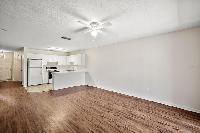 unfurnished living room with ceiling fan, sink, a textured ceiling, and light hardwood / wood-style flooring