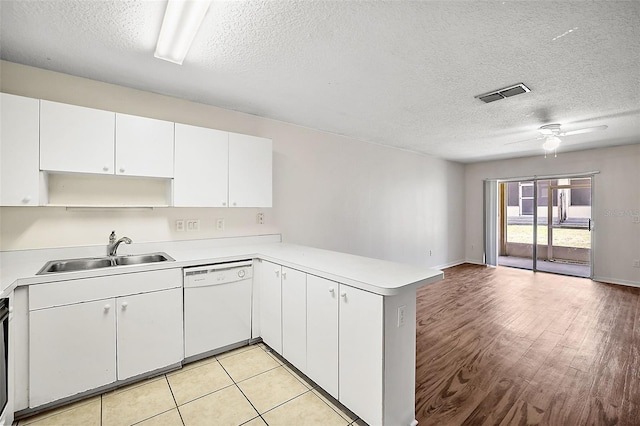 kitchen with white dishwasher, sink, white cabinets, and kitchen peninsula