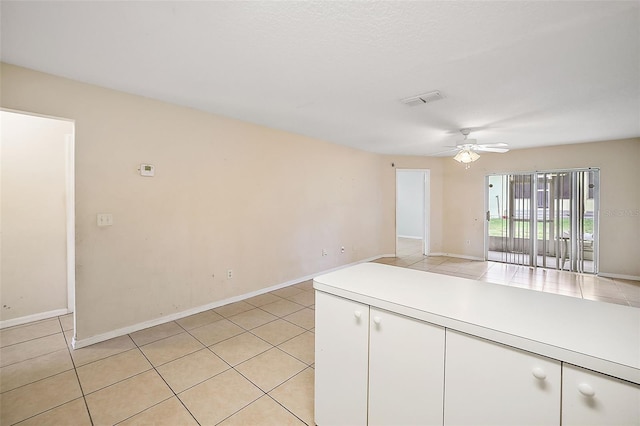 kitchen featuring ceiling fan, white cabinets, and light tile patterned flooring