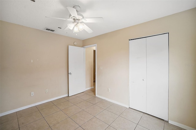 unfurnished bedroom featuring ceiling fan, light tile patterned floors, and a closet