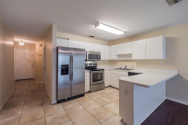 kitchen with white cabinets, appliances with stainless steel finishes, and light tile patterned floors