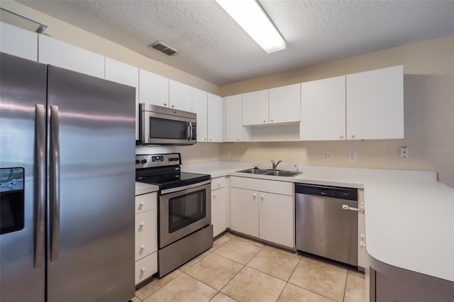 kitchen featuring light tile patterned floors, white cabinetry, appliances with stainless steel finishes, a textured ceiling, and sink