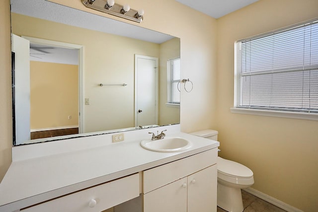 bathroom with plenty of natural light, toilet, vanity, and tile patterned flooring