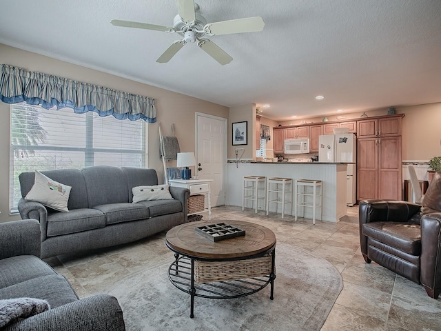 living room featuring ceiling fan and a textured ceiling