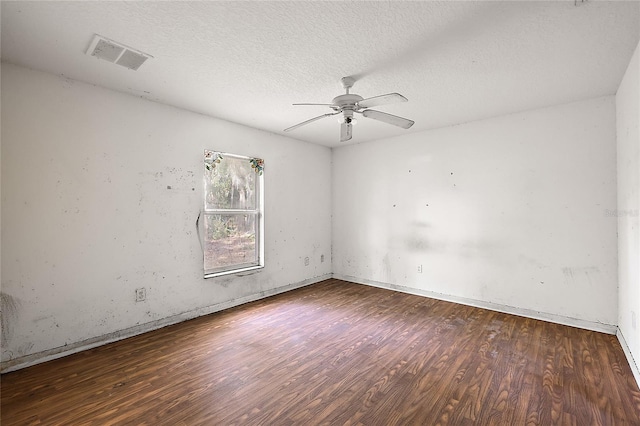 empty room with ceiling fan, dark wood-type flooring, and a textured ceiling