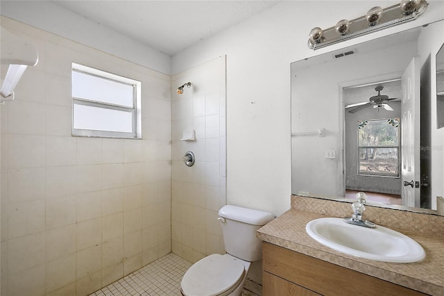 bathroom with toilet, tiled shower, and vanity