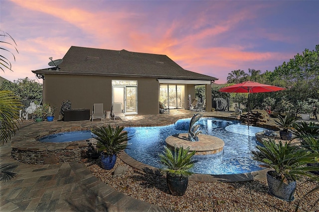 pool at dusk featuring an in ground hot tub and a patio