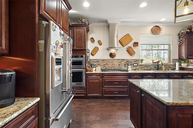 kitchen featuring exhaust hood, appliances with stainless steel finishes, decorative backsplash, dark hardwood / wood-style flooring, and light stone counters