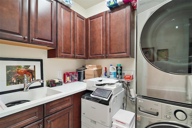 laundry room with cabinets, stacked washer / dryer, and sink