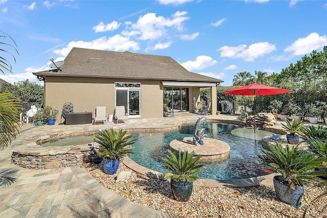 rear view of property with a pool with hot tub, pool water feature, and a patio