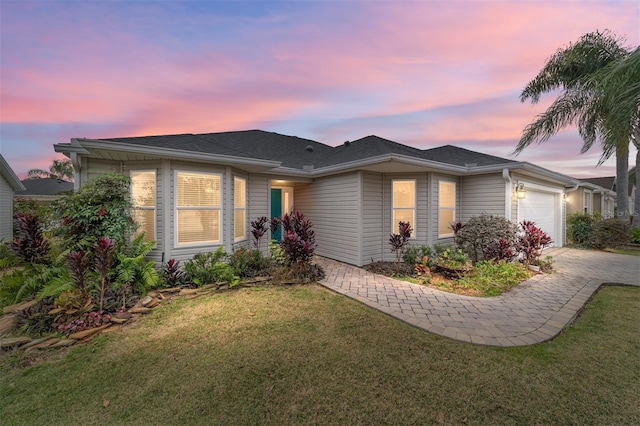 single story home with a front lawn, decorative driveway, and an attached garage