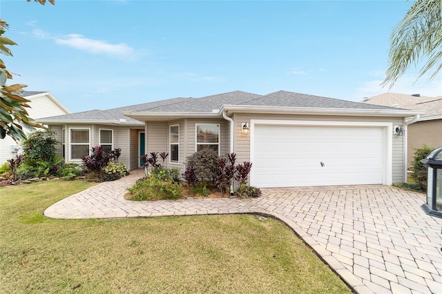 ranch-style home with a garage, a front yard, decorative driveway, and a shingled roof