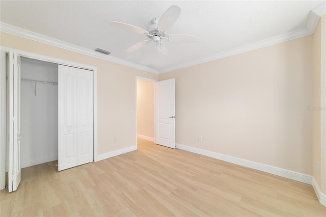 unfurnished bedroom with ornamental molding, light wood-type flooring, ceiling fan, and a closet