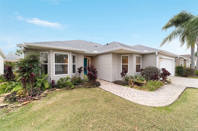 ranch-style home with a garage, a shingled roof, a front lawn, and decorative driveway