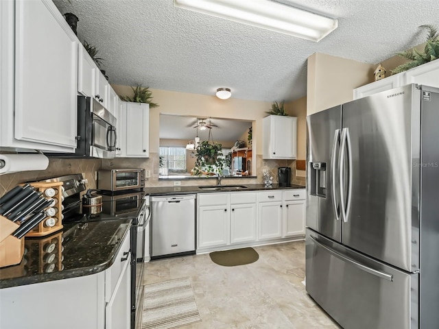 kitchen with sink, backsplash, white cabinets, and appliances with stainless steel finishes