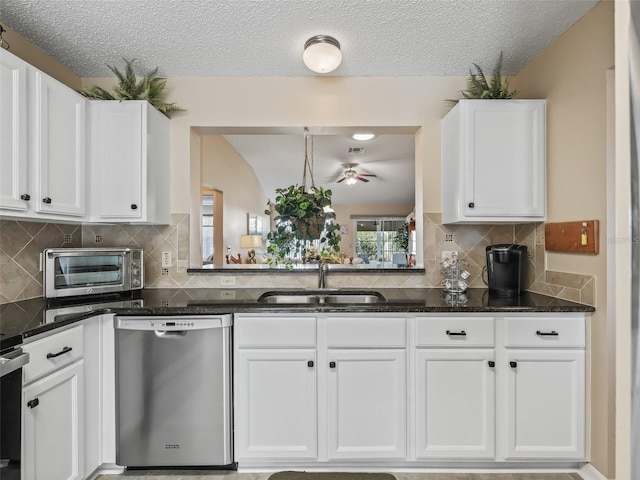 kitchen with sink, white cabinets, decorative backsplash, stainless steel dishwasher, and dark stone counters