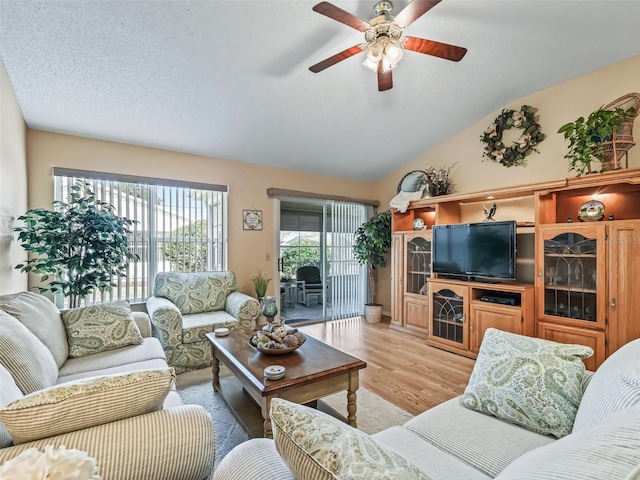 living room featuring ceiling fan, lofted ceiling, a textured ceiling, and light wood-type flooring