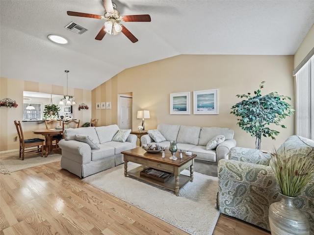 living room with lofted ceiling, a textured ceiling, ceiling fan, and light wood-type flooring