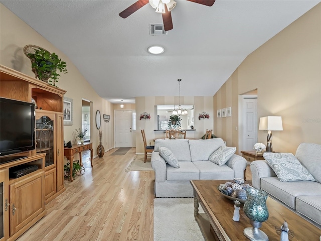 living room with lofted ceiling, ceiling fan with notable chandelier, and light hardwood / wood-style flooring