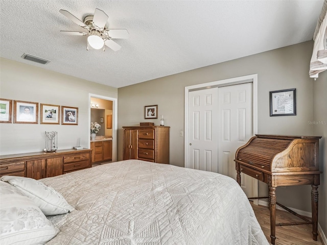 bedroom featuring ensuite bathroom, wood-type flooring, ceiling fan, a textured ceiling, and a closet