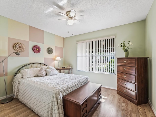 bedroom with hardwood / wood-style flooring, ceiling fan, and a textured ceiling