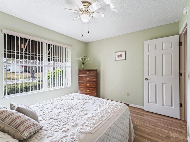 bedroom with ceiling fan, wood-type flooring, and a textured ceiling