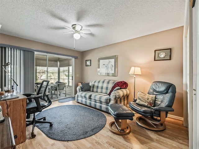 living room featuring ceiling fan, hardwood / wood-style floors, and a textured ceiling