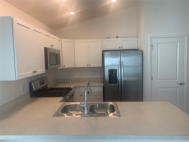 kitchen with lofted ceiling, white cabinets, sink, and stainless steel appliances