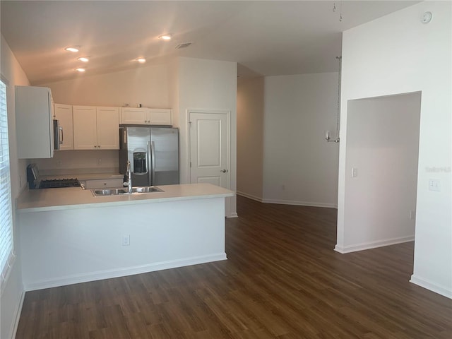 kitchen featuring white cabinets, sink, stainless steel fridge with ice dispenser, vaulted ceiling, and stove