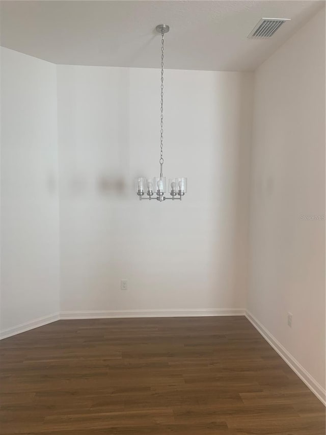 unfurnished room with dark hardwood / wood-style flooring and a notable chandelier