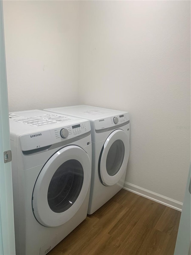 clothes washing area with dark wood-type flooring and separate washer and dryer