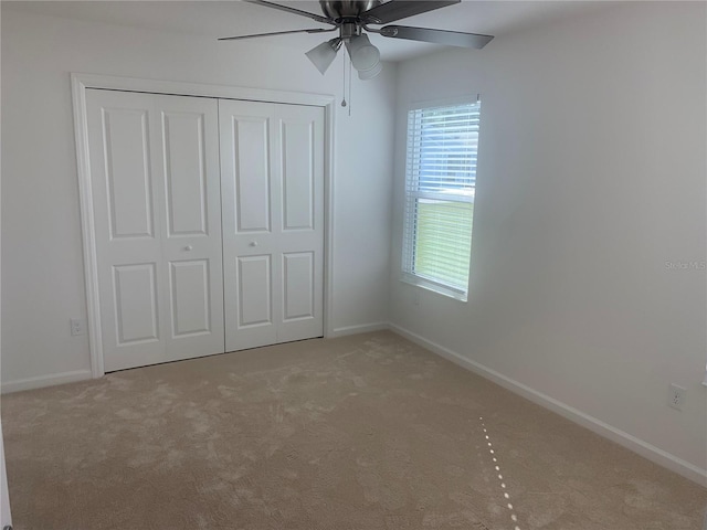 unfurnished bedroom featuring light carpet, ceiling fan, and a closet