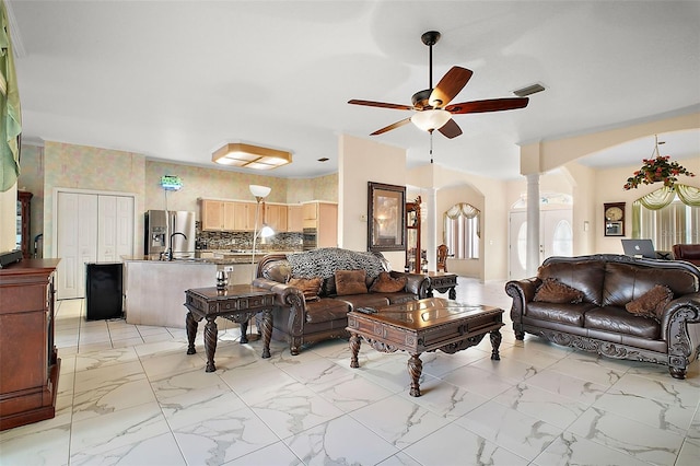 living room featuring ornate columns and ceiling fan