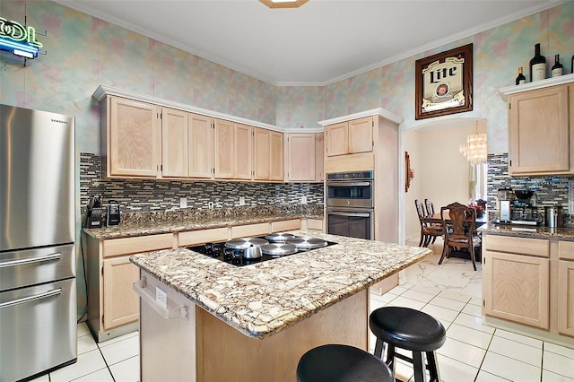 kitchen with a kitchen breakfast bar, light brown cabinets, stainless steel appliances, and a center island