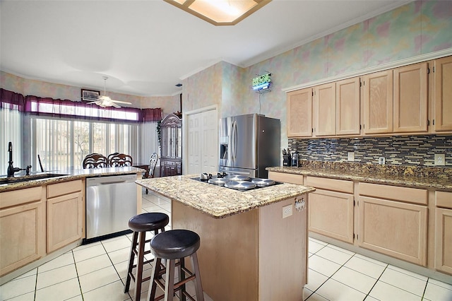 kitchen with a center island, sink, appliances with stainless steel finishes, light brown cabinets, and light tile patterned floors