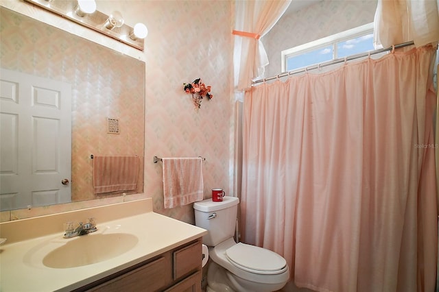 bathroom with toilet, vanity, and walk in shower