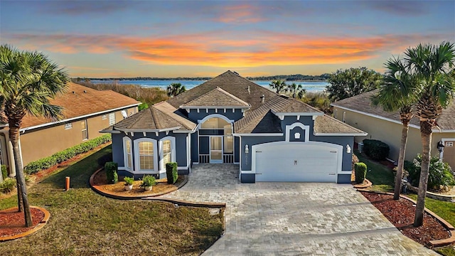 view of front of home with a garage, a lawn, and a water view