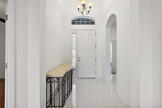 tiled entryway featuring a towering ceiling and a notable chandelier