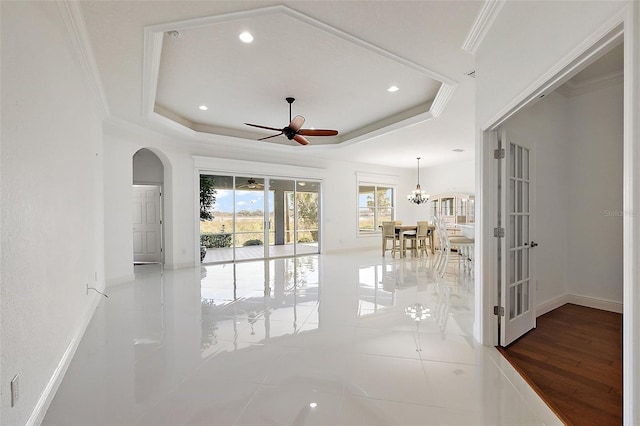 interior space with ceiling fan with notable chandelier, a raised ceiling, crown molding, and tile patterned flooring