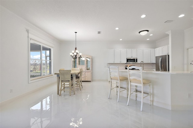 kitchen featuring appliances with stainless steel finishes, decorative light fixtures, tasteful backsplash, white cabinetry, and light tile patterned floors