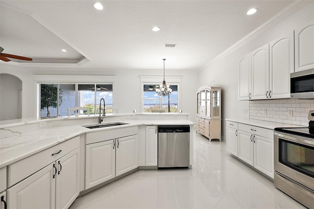 kitchen with pendant lighting, white cabinetry, stainless steel appliances, tasteful backsplash, and sink