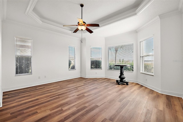 unfurnished room featuring hardwood / wood-style flooring, ceiling fan, crown molding, and a tray ceiling