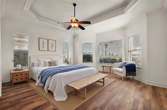 bedroom with ceiling fan, hardwood / wood-style floors, ornamental molding, and a raised ceiling