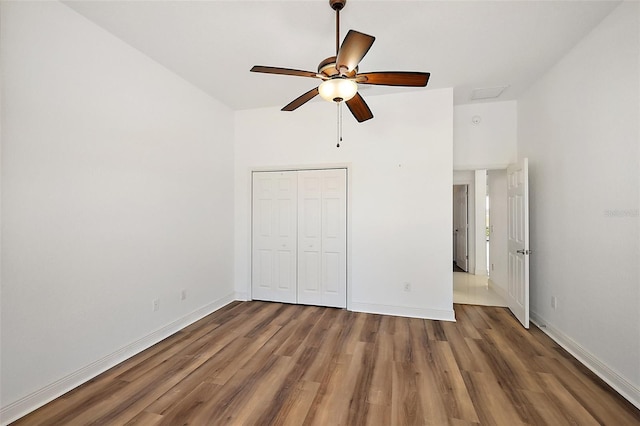 unfurnished bedroom with ceiling fan, wood-type flooring, and a closet