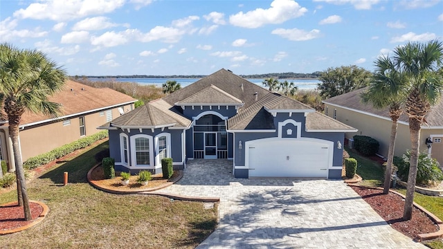 view of front facade featuring a garage, a front yard, and a water view