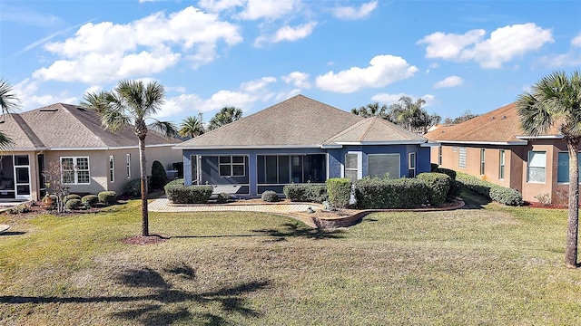 rear view of house featuring a yard and a sunroom